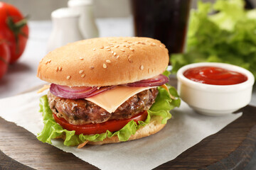 Tasty hamburger with patty, cheese and vegetables served on table, closeup