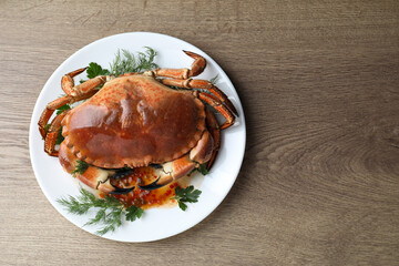 Delicious crab with greens on wooden table, top view. Space for text