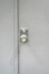 Close-up at closed white steel door with chrome door's knob. Selective focus.