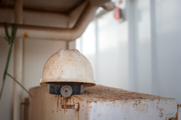 The dirty white safety helmet of hardhat for construction worker, that placed on the metal part. Industrial safety equipment object photo.