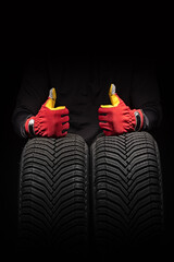 Car tire service and hands of mechanic holding new tyre on black background with copy space for text