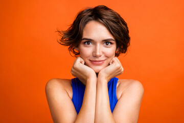 Photo of stunning positive peaceful lady hands touch cheeks isolated on vivid orange color background