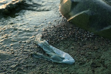 Used plastic bag near water at beach. Environment pollution