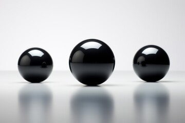  a group of black balls sitting next to each other on a white surface with a white wall in the background of the picture and a white wall in the background.