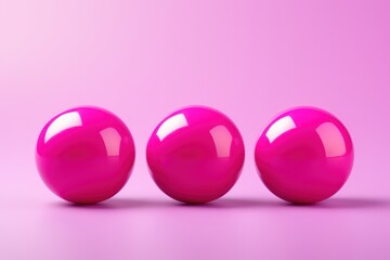  a group of three pink balls sitting on top of a pink surface with a light pink back ground and a light pink back ground in the middle of the picture.