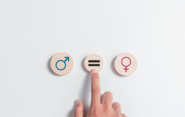 Hand touching circles wooden block with icons men and women for equality between men and women....
