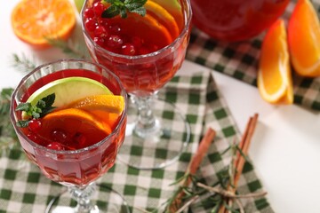Christmas Sangria cocktail in glasses and ingredients on white table, closeup. Space for text