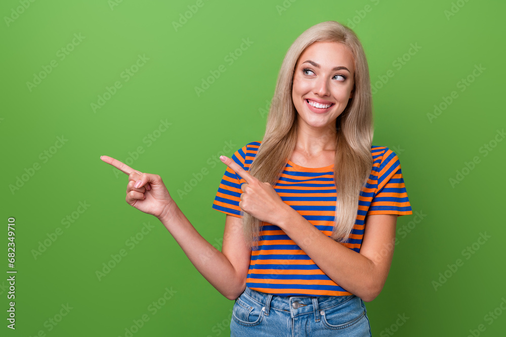 Canvas Prints Photo of adorable cute girl in trendy clothes outfit looking billboard brand collection empty space isolated on green color background