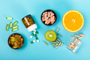 Vitamins and supplements. Variety of vitamin tablets in a jar on a texture background.Multivitamins with fresh and healthy fruits.Food supplements. Flat lay. Space for text.Copy space