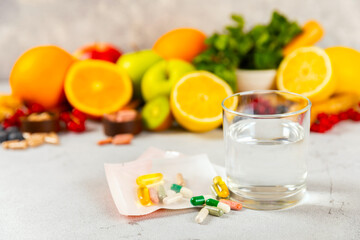 Vitamins and supplements. Variety of vitamin tablets with a glass of water on a texture background. Multivitamin complex for every day. Nutritional supplements. It's time to take your pills. Flat lay.