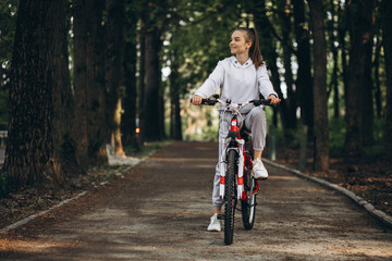 Naklejka premium Young sporty woman riding bicycle in the park