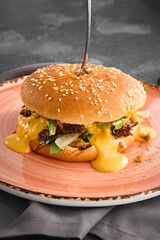 A succulent pulled beef burger dripping with rich cheese sauce, served on a plate for a mouthwatering meal