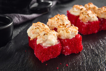 Succulent baked California roll topped with creamy crab, coated in a crispy tobiko crust, served on an elegant black slate