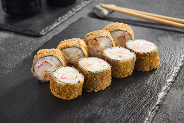 Crispy tempura roll filled with crab and shrimp, perfectly golden-brown, served on a minimalist black slate