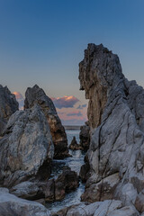 seascape with strangely shaped rocks and red clouds at sunset