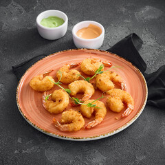 Crispy tempura shrimp elegantly arranged on a round ceramic plate, ready to be enjoyed, against a dark, textured background