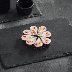 Droplet sushi roll featuring a fluffy Japanese omelet and tobiko caviar, tastefully arranged on a dark slate serving board