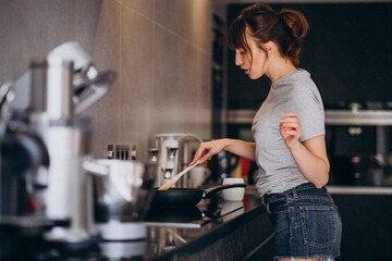 Young woman preparing breakfast in kitchen in the morning