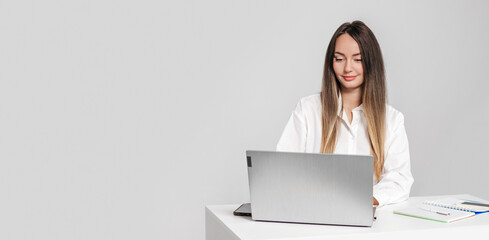 girl psychologist sitting at a table with a laptop smiling isolated on a white background
