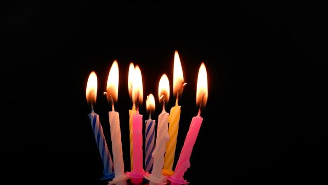 Birthday candles burning and melting on black background. 