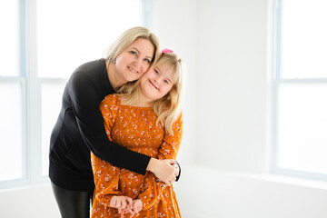 Mother and sweet down syndrome daughter girl at home