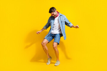 Fototapeta na wymiar Full size photo of overjoyed guy wear jeans jacket shorts in sunglass having fun at disco party isolated on yellow color background