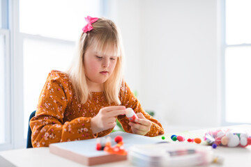 Portrait of beautiful little girl having down syndrome doing Arts and Crafts