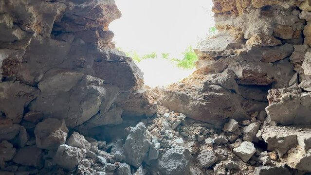 Through hole in the wall video of  green meadow, hole in shell rock wall caused by an artillery shot during war in Ukraine. hole artillery shot
