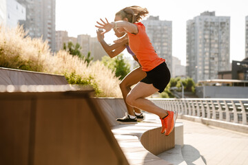 Two active fitness women jumping during workout outdoors
