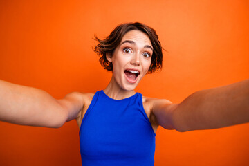 Photo of shiny impressed girl dressed blue top open mouth tacking selfie isolated orange color background