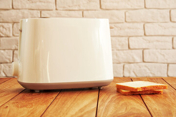 White electric toaster with toasted bread on the wooden table. Home cooking and kitchen theme - obrazy, fototapety, plakaty