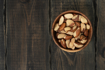 Peeled brazil nut in wooden cup on decorative wooden background