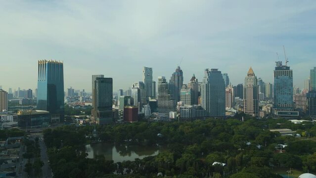 Aerial view of skyscraper buildings with green trees in Lumpini Park, Sathorn district, Bangkok Downtown Skyline. Thailand.