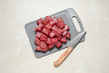 Cooking delicious goulash. Raw beef meat and knife on light grey table, top view