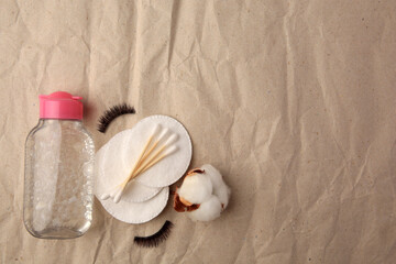 Flat lay composition with makeup remover and cotton flower on crumpled paper, space for text