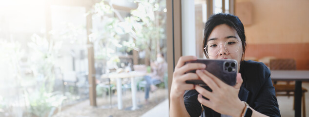 Young women enjoying coffee, using smart phone in cafe-panoramic banner