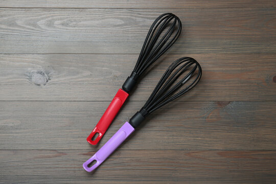 Two whisks on wooden table, top view. Kitchen tool