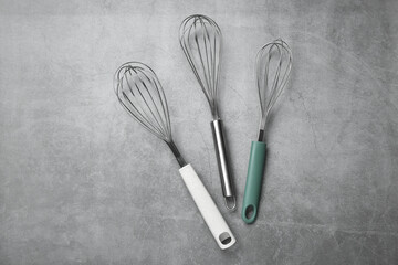 Metal whisks on gray table, top view