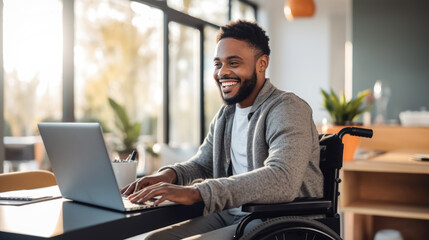 Smiling man in a wheelchair works on laptop in his home office. - obrazy, fototapety, plakaty