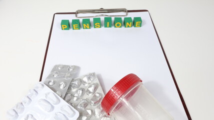 Singola parola "PENSIONE" su blocco di legno, tasse isolate, con sfondo di scrivania di un ufficio medico. © barbacane