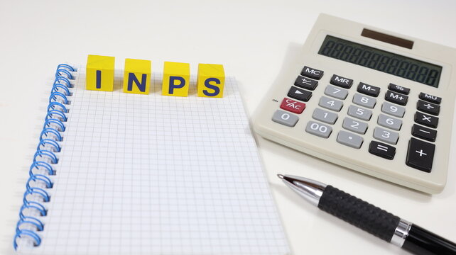 Singola parola "INPS" su blocco di legno, tasse isolate, con sfondo scrivania da ufficio.