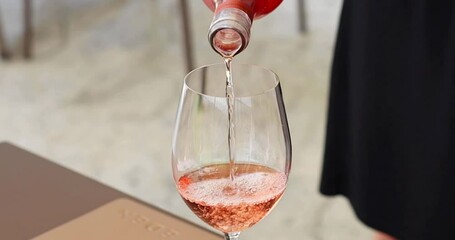 Woman pouring rose wine in the glass close up view