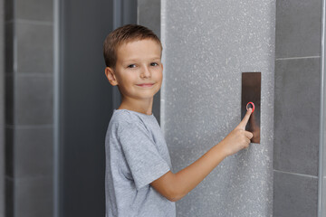 Boy tries to push the elevator button up and down. Child stretches out his hand and finger to press the button © Studio Peace