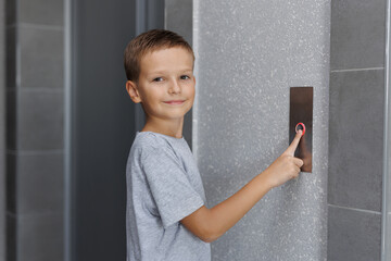 Boy tries to push the elevator button up and down. Child stretches out his hand and finger to press...