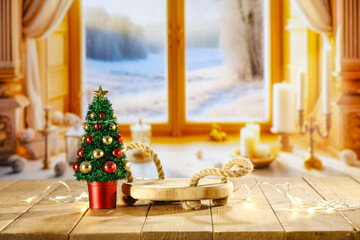 Wooden desk of empty space for your decoration. Christmas tree and lights. Blurred window sill background with winter view. Winter landscape and cold december day. Christmas mockup and pedestal. 