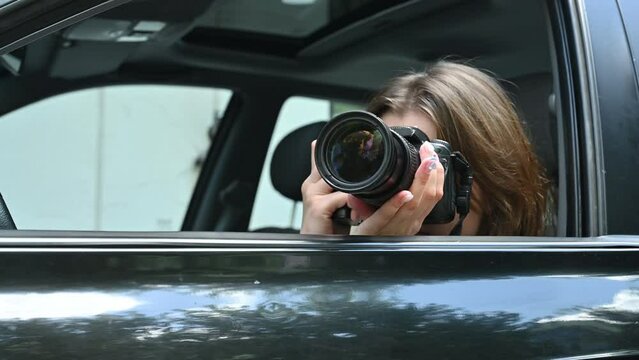 Young woman funny spying and taking photo of someone from car window. Close up