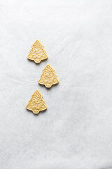 Top view of cut out raw sugar cookie dough shaped like christmas tree, Christmas tree sugar cookie dough about to be baked, process of making sugar cookies