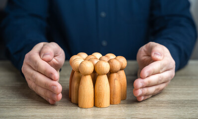 A man protects human figures with his hands. The concept of security and social protection. Health...