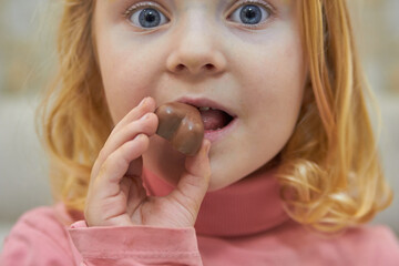 close up of a little girl biting a chocolate candy,surprised child eats heart chocolates