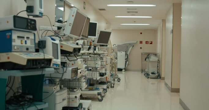 Handheld Documentary Style Shot Of Empty Hospital Corridor With Medical Equipment Electrical Machines. Patient Monitor For State Of Health During And After Surgery. EKG And ECG Machines For Heart